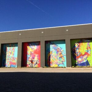 Four of Adrian Torres' large murals at Legacy Central with a man jumping in front for scale