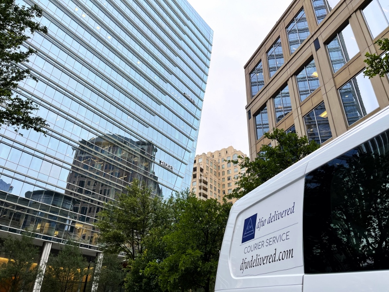 A courier van next to the McKinney and Olive building in uptown Dallas