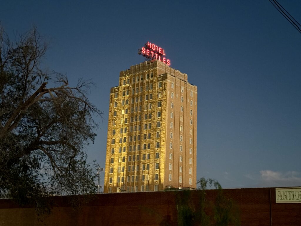 A tall mid-century hotel building at night.